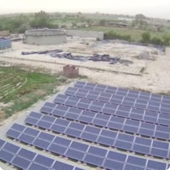 Solar array powering a community biogas plant, with the digester tank behind