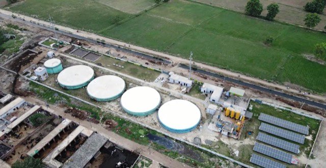 Aerial view of the Gujjar Colony biogas plant, Lahore — five digester tanks with the on-site solar array